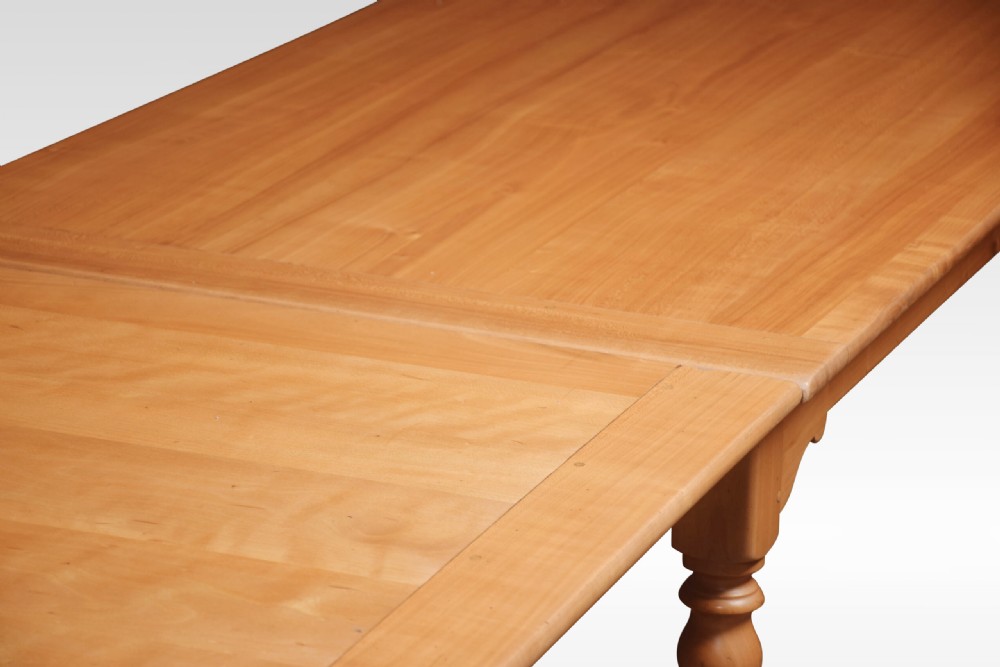 A large fruitwood farmhouse dining table featuring a framed plank top with breadboard ends and turned legs. View IV