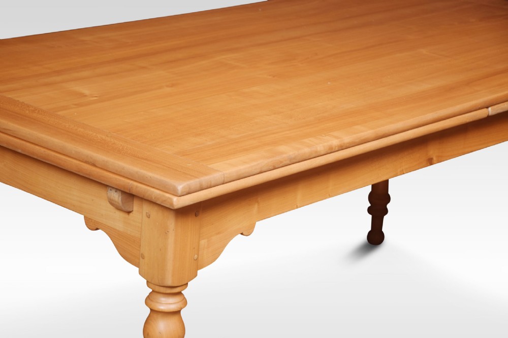 A large fruitwood farmhouse dining table featuring a framed plank top with breadboard ends and turned legs. View V