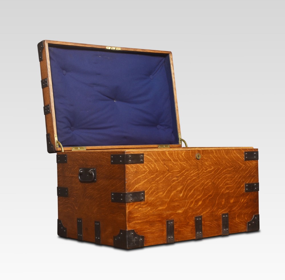 A 19th-century oak silver chest reinforced with black iron corner brackets and strapwork, shown with its lid open to display a blue padded fabric interior lining.
