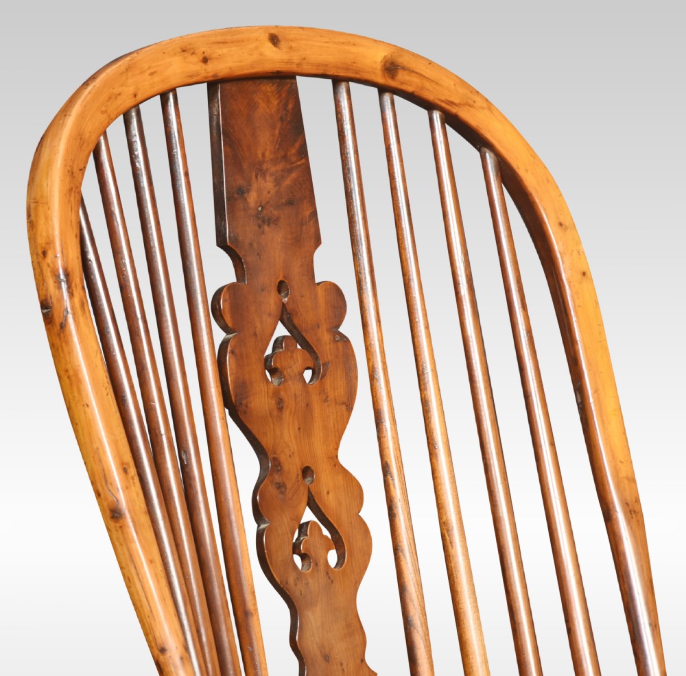 A nineteenth-century yew wood Windsor armchair with a high hoop back, pierced central splat, turned legs, and curved arm supports. View VI