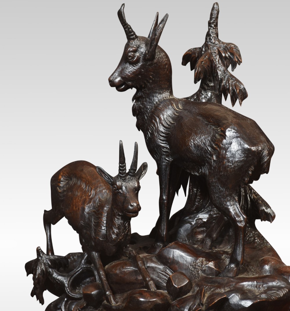 A nineteenth-century Black Forest carved wood mantel clock garniture set featuring sculpted alpine chamois figures atop rocky outcrops. View X