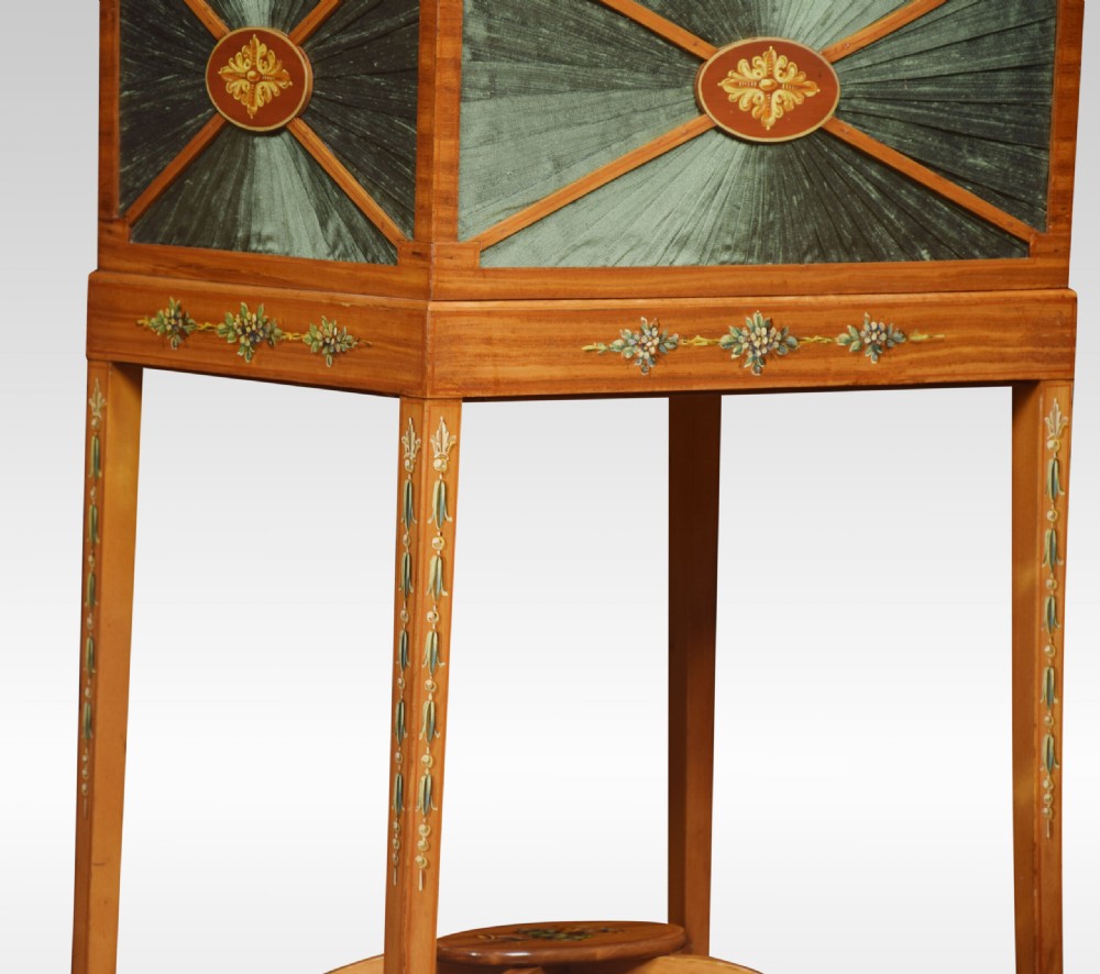 An antique painted satinwood ladies sewing table featuring open lid storage, pleated green silk side panels, and hand-painted floral decorations on tapered legs. View VI