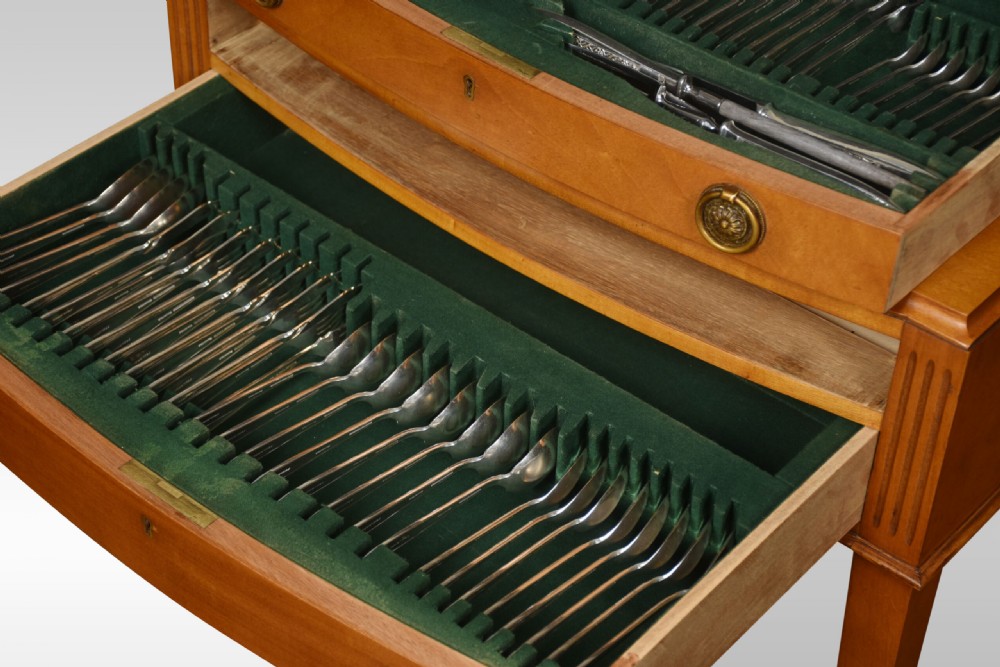 A walnut cutlery canteen table featuring two open drawers lined with green felt filled with silver flatware, resting on tapered legs. View III