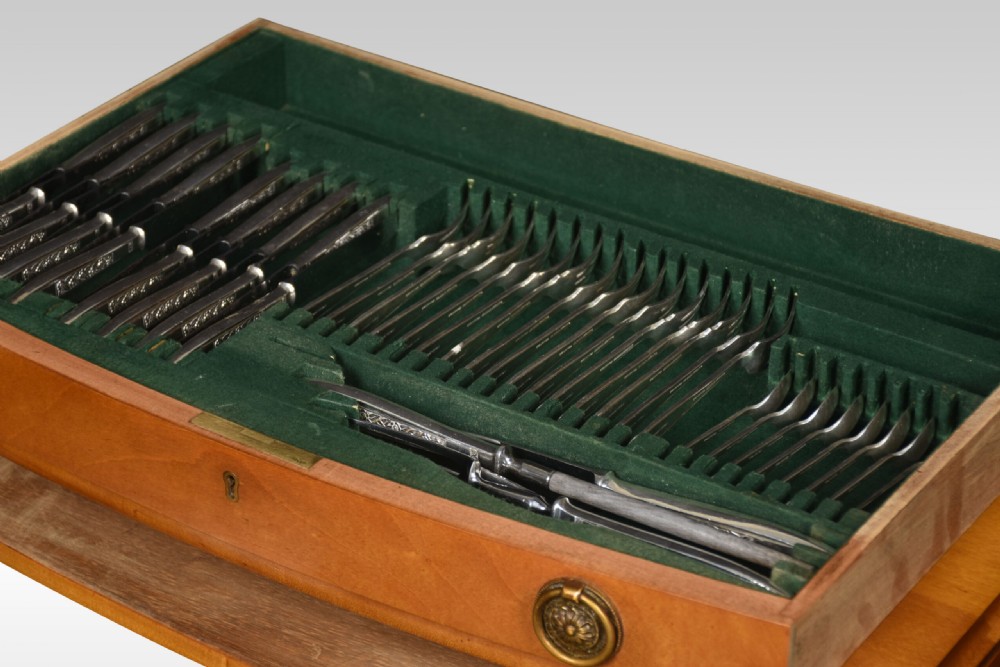 A walnut cutlery canteen table featuring two open drawers lined with green felt filled with silver flatware, resting on tapered legs. View IV
