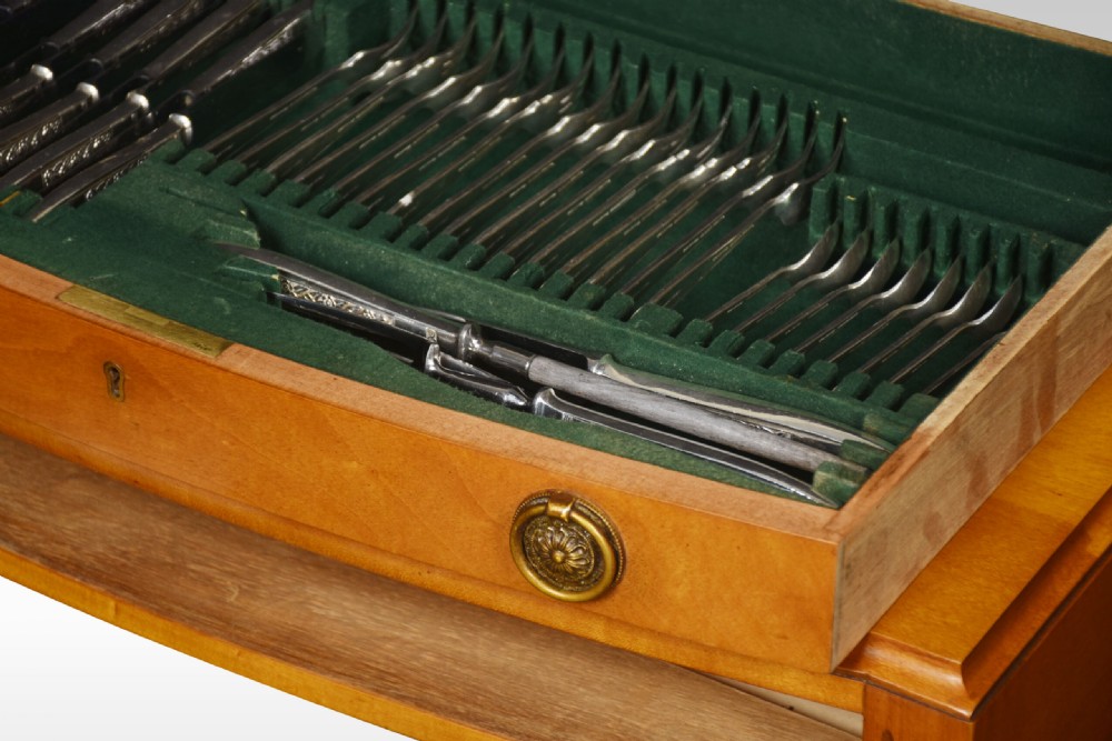 A walnut cutlery canteen table featuring two open drawers lined with green felt filled with silver flatware, resting on tapered legs. View V