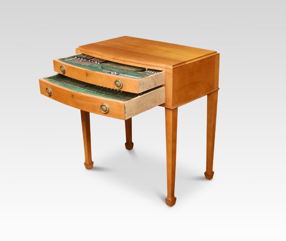 A walnut cutlery canteen table featuring two open drawers lined with green felt filled with silver flatware, resting on tapered legs. View VII
