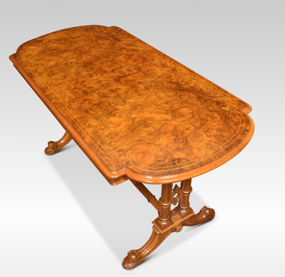An antique Victorian burr walnut centre table featuring a figured inlaid top, twin turned column supports, a turned stretcher, and carved scrolled feet. View III