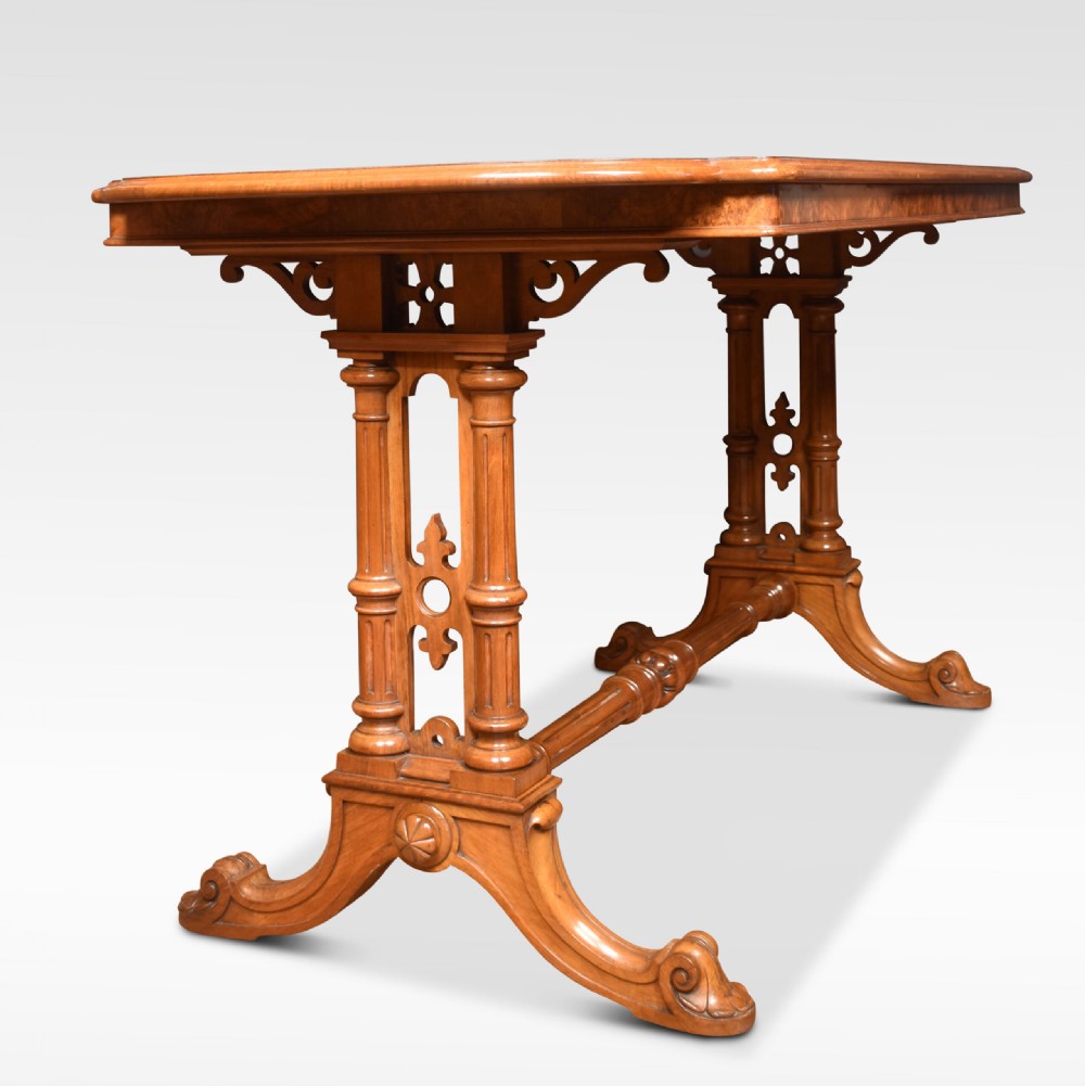 An antique Victorian burr walnut centre table featuring a figured inlaid top, twin turned column supports, a turned stretcher, and carved scrolled feet. View VI
