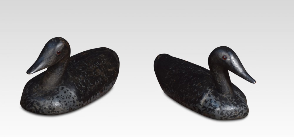 A set of three hand-carved wooden bird decoys painted in dark grey and black with mottled detailing and inset eyes. View II