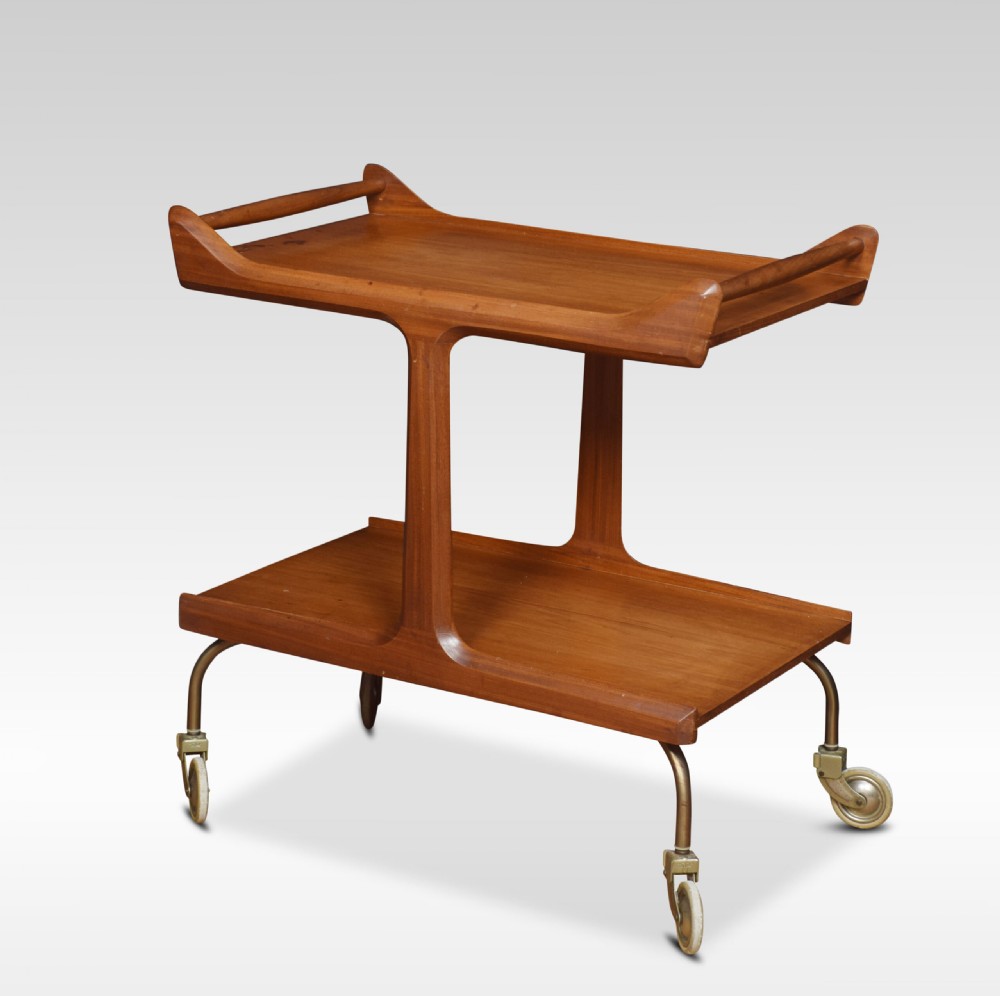 A mid-century modern two-tier walnut drinks trolley with sculpted handles and brass castors. View II