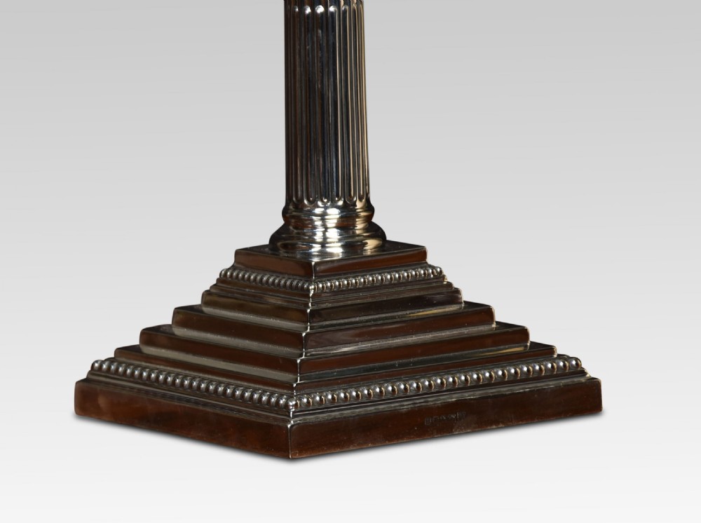 A silver-plated Corinthian column table lamp with a reeded shaft, stepped square base, and a pleated champagne shade. View VI