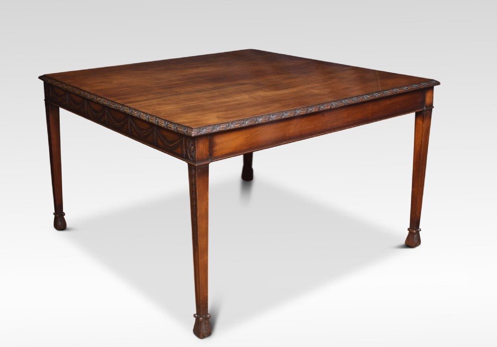 An Adam Revival mahogany centre table featuring a square top with carved edge moulding, a drapery-carved apron, and four tapered square legs.