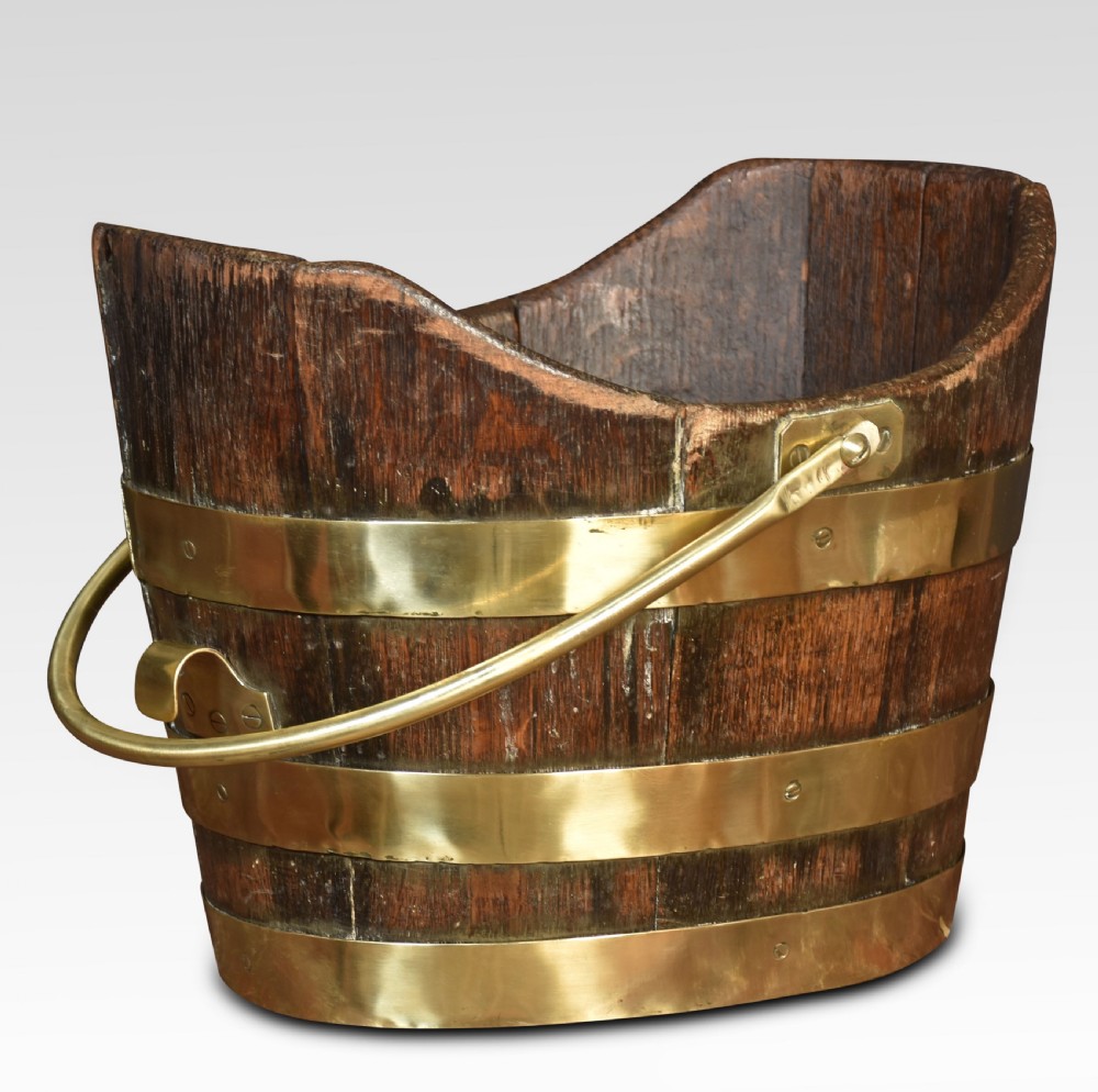 A George III coopered wooden peat bucket featuring a curved scoop rim, brass binding hoops, and a brass swing handle.