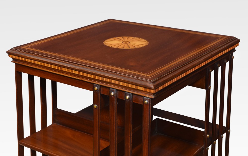A pair of Edwardian inlaid mahogany revolving bookcases featuring square tops with satinwood crossbanding, vertical slat sides, and rotating bases on castors. View VI