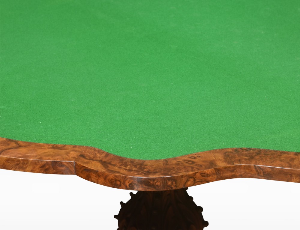 An antique Victorian burr walnut card table featuring a shaped serpentine top lined with green baize, resting on a carved pedestal stem and tripod cabriole legs. View III