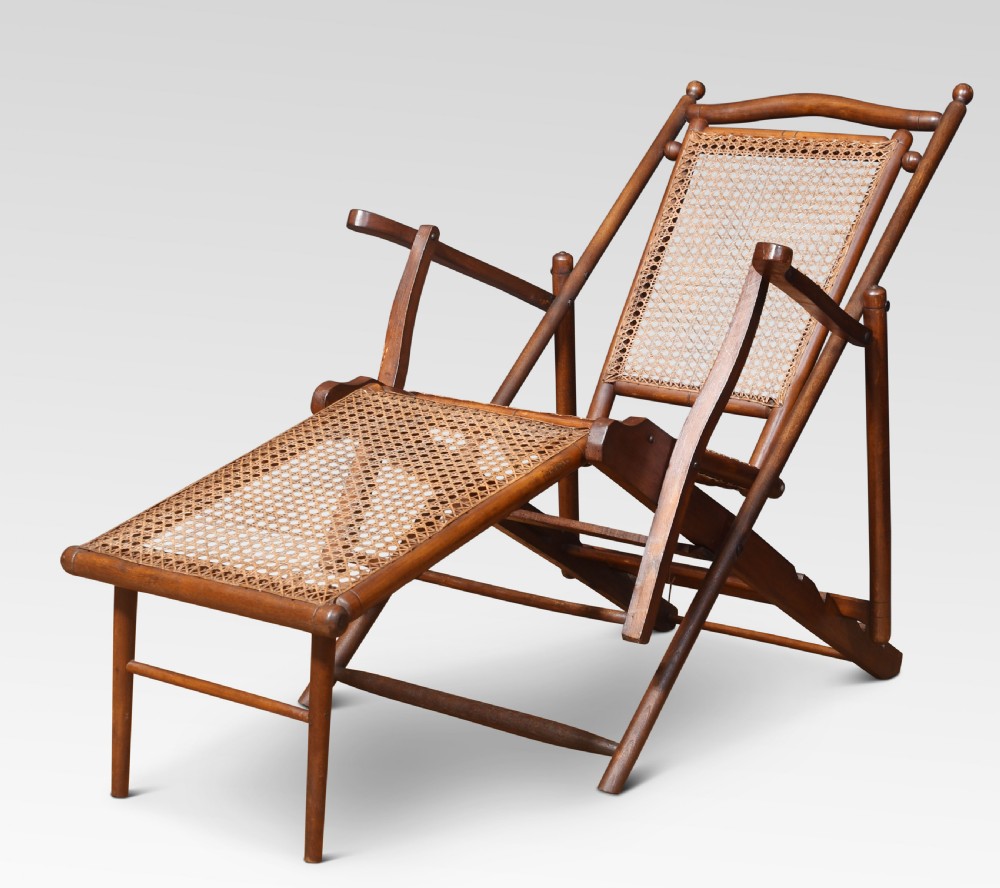 A Victorian walnut folding steamer deck chair with hand-caned backrest and extended footrest.