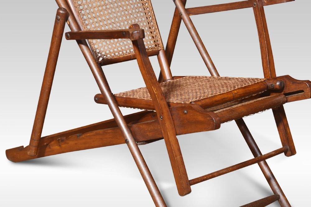 A Victorian walnut folding steamer deck chair with hand-caned backrest and extended footrest. View VII