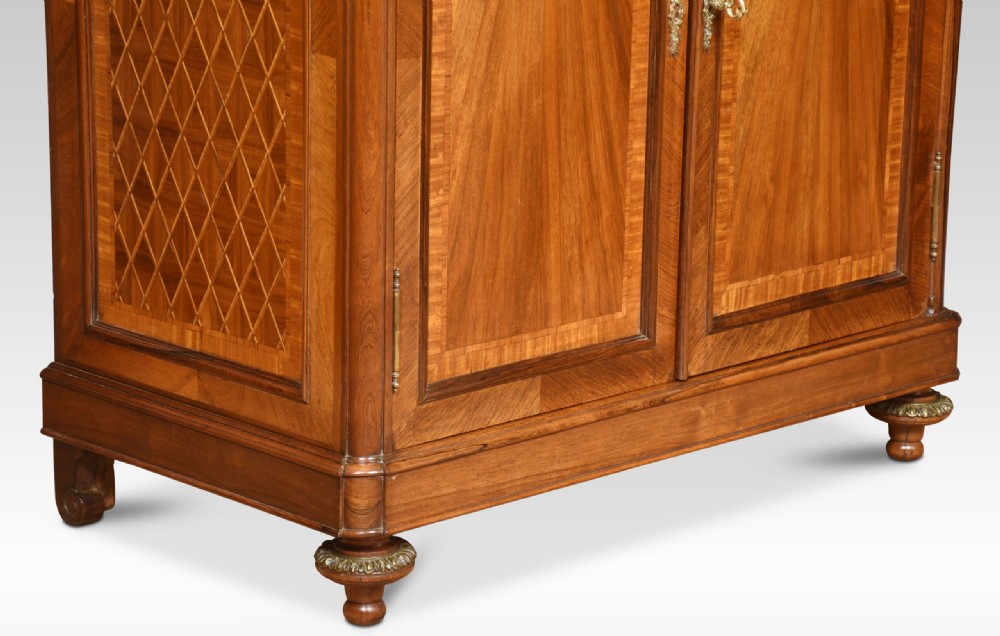 An antique French walnut display cabinet featuring a upper glazed vitrine with glass shelves, an arched crest, and a lower cupboard with sunburst parquetry veneer panels. View III
