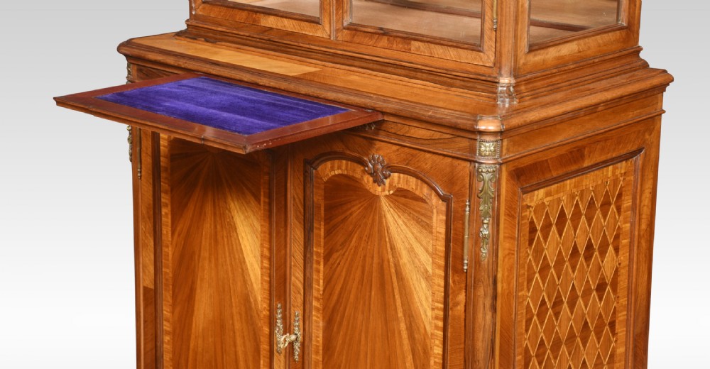 An antique French walnut display cabinet featuring a upper glazed vitrine with glass shelves, an arched crest, and a lower cupboard with sunburst parquetry veneer panels. View X