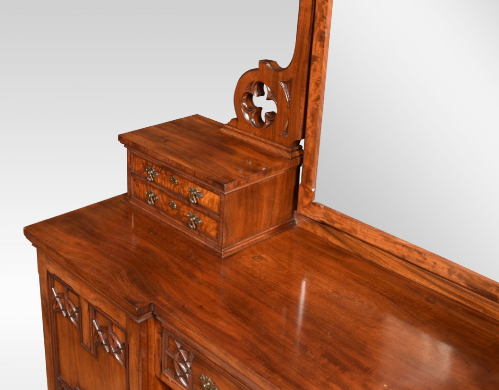 An antique Gothic Revival mahogany dressing table featuring a central adjustable mirror, raised trinket drawers, and carved tracery cupboard doors. View IX