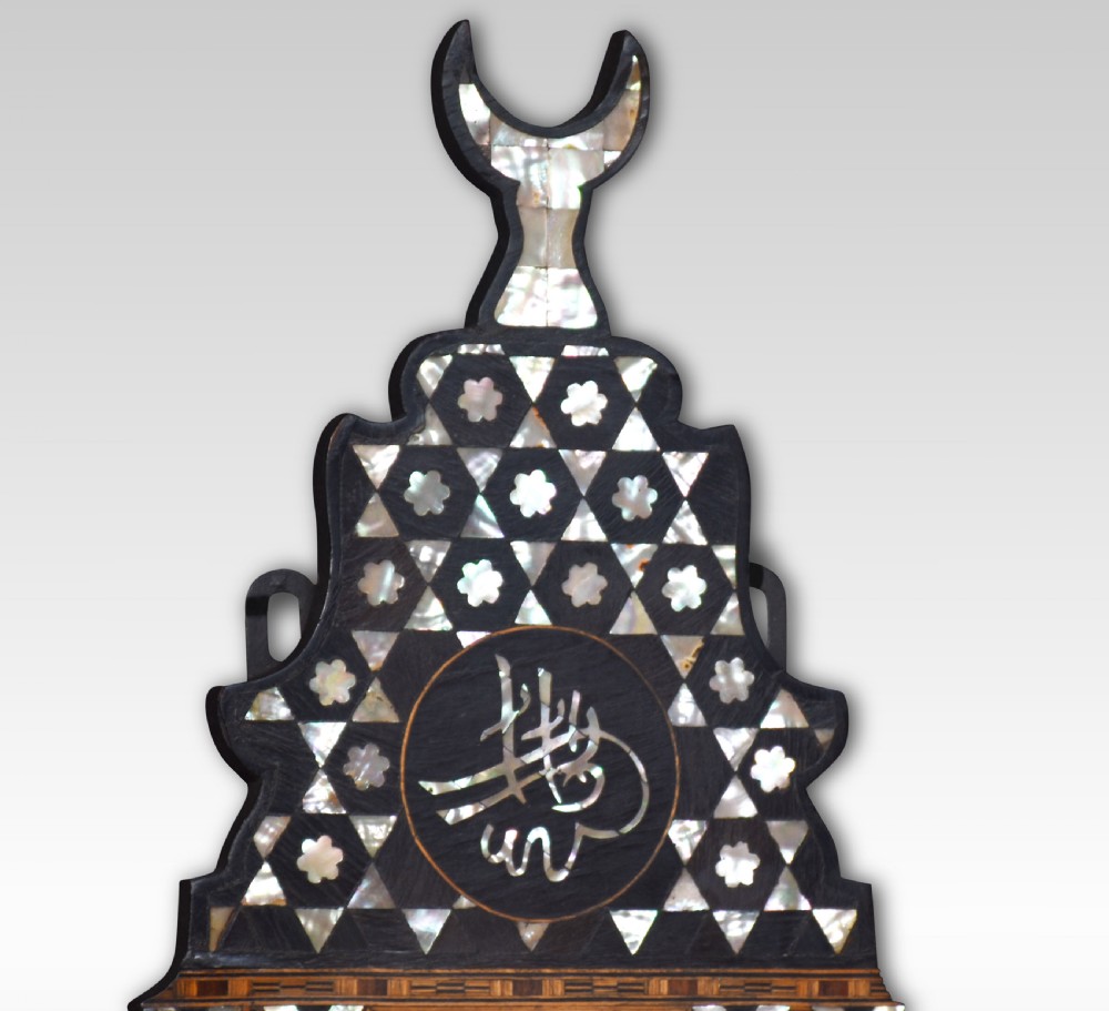 A dark hardwood Moorish wall bracket with geometric mother-of-pearl inlay, featuring a crescent moon finial and calligraphic medallion. View IV