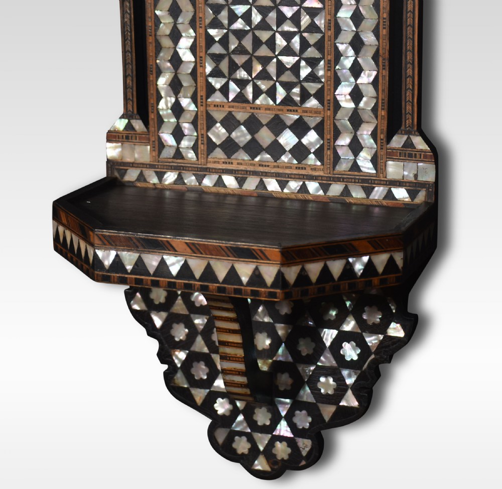A dark hardwood Moorish wall bracket with geometric mother-of-pearl inlay, featuring a crescent moon finial and calligraphic medallion. View VI
