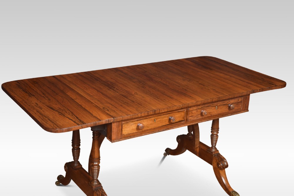 A Regency rosewood sofa table with two drop flaps, two frieze drawers with turned timber knobs, double pillar supports, and splayed legs ending in brass castors. View III