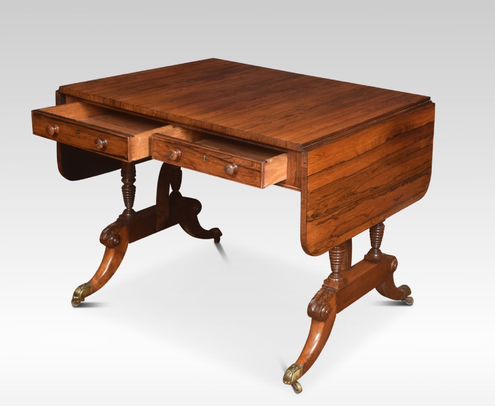 A Regency rosewood sofa table with two drop flaps, two frieze drawers with turned timber knobs, double pillar supports, and splayed legs ending in brass castors. View IX