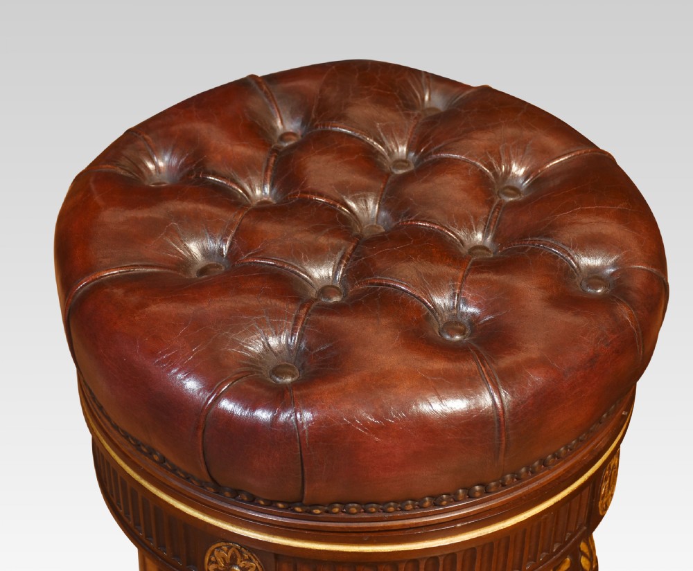 A pair of 19th-century circular adjustable stools featuring deep button-tufted chestnut brown leather upholstery, parcel-gilded details, and fluted turned legs. View VI
