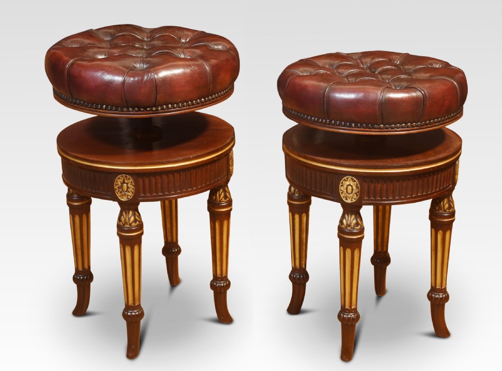 A pair of 19th-century circular adjustable stools featuring deep button-tufted chestnut brown leather upholstery, parcel-gilded details, and fluted turned legs. View VIII