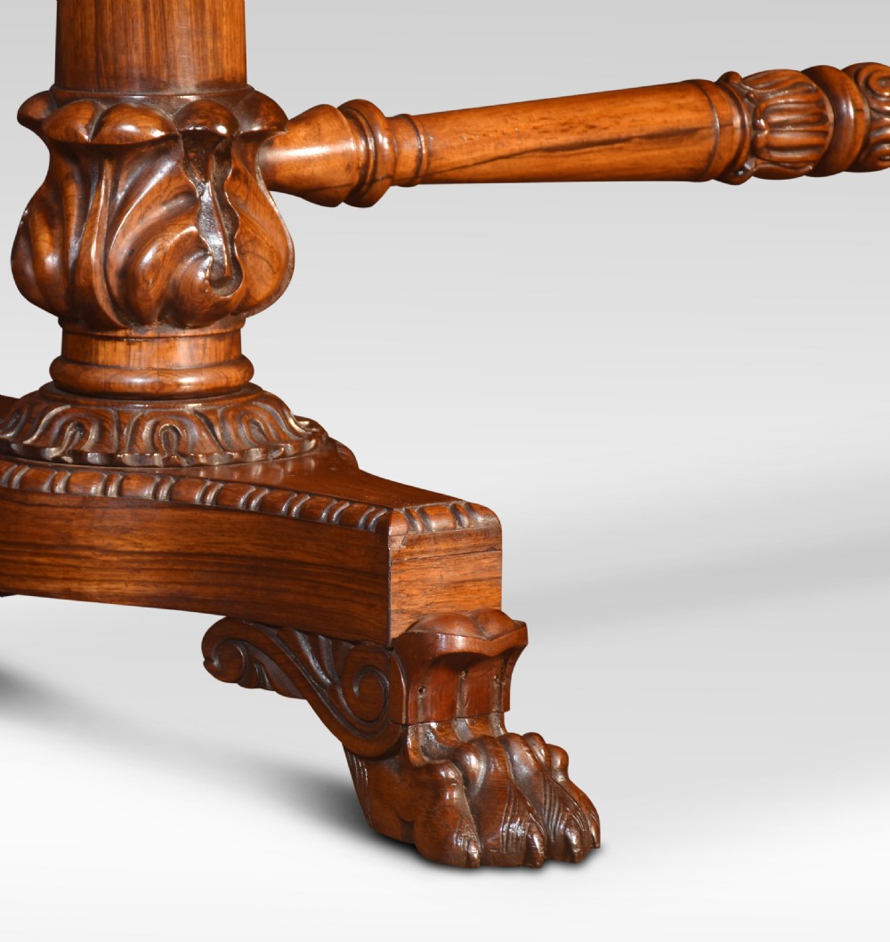 A Regency rosewood library table featuring a rectangular top, twin carved pedestal supports, a turned cross stretcher, and lion paw feet. View VII