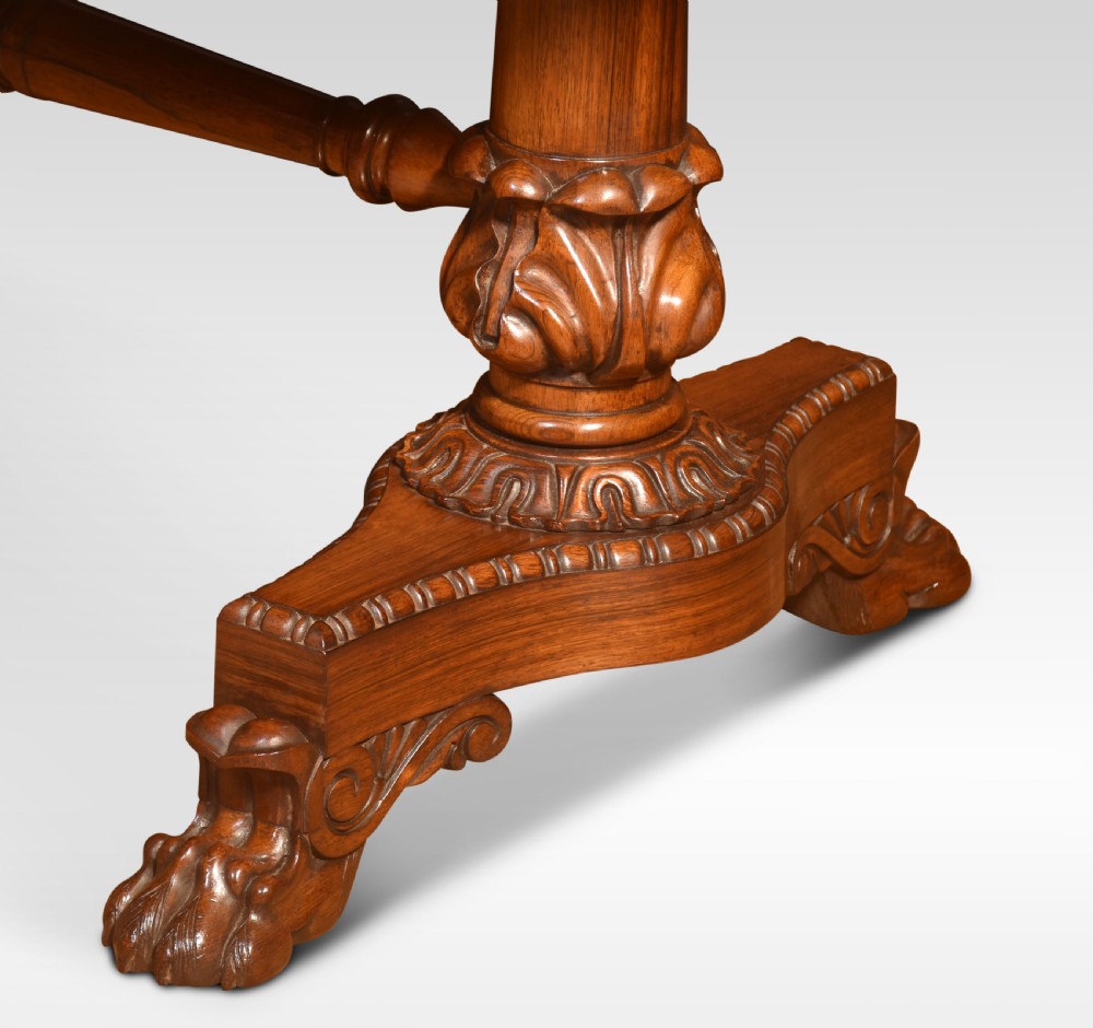A Regency rosewood library table featuring a rectangular top, twin carved pedestal supports, a turned cross stretcher, and lion paw feet. View XI