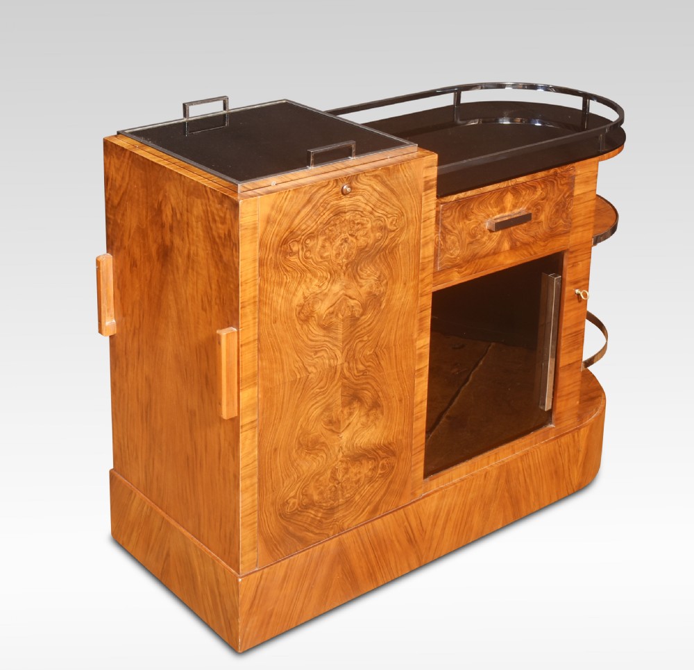 An Art Deco walnut drinks trolley featuring a central revolving glass holder, chrome gallery rail, a single drawer, and a lower glass-fronted storage cabinet. View II