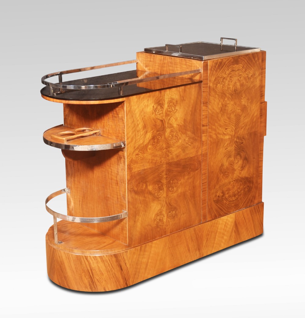 An Art Deco walnut drinks trolley featuring a central revolving glass holder, chrome gallery rail, a single drawer, and a lower glass-fronted storage cabinet. View VIII