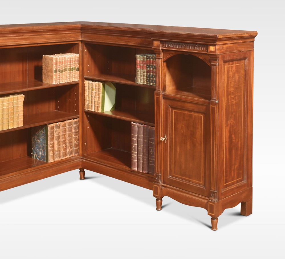 An L-shaped antique mahogany open corner bookcase featuring satinwood inlaid stringing, central open shelves, and flanking side cupboards. View II