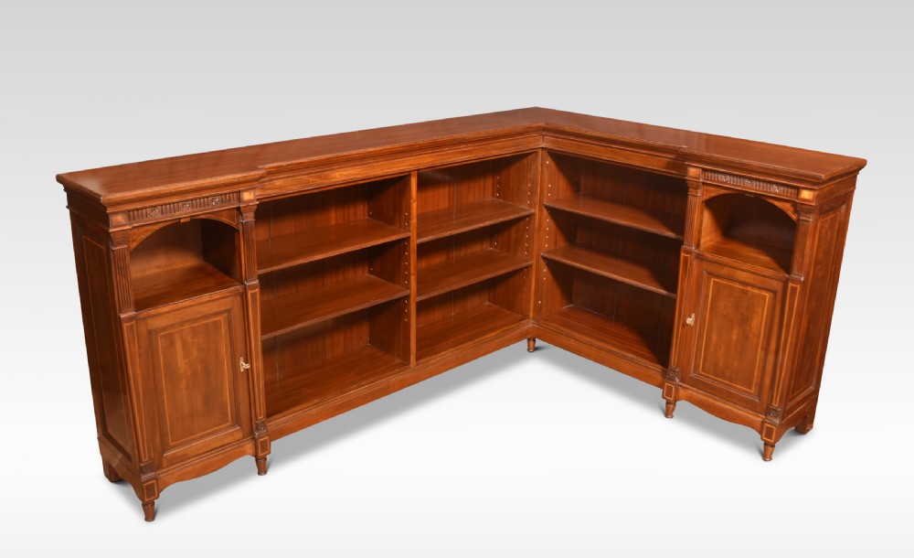 An L-shaped antique mahogany open corner bookcase featuring satinwood inlaid stringing, central open shelves, and flanking side cupboards. View VIII