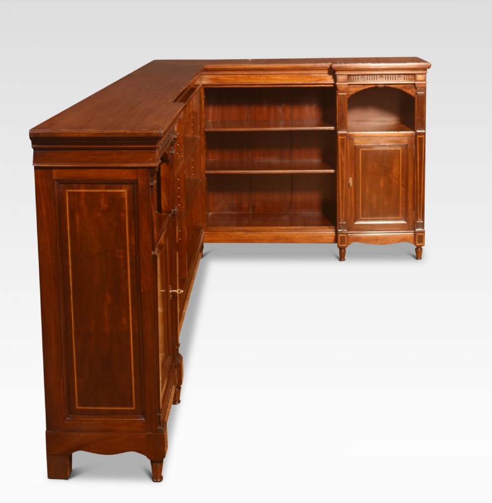 An L-shaped antique mahogany open corner bookcase featuring satinwood inlaid stringing, central open shelves, and flanking side cupboards. View IX