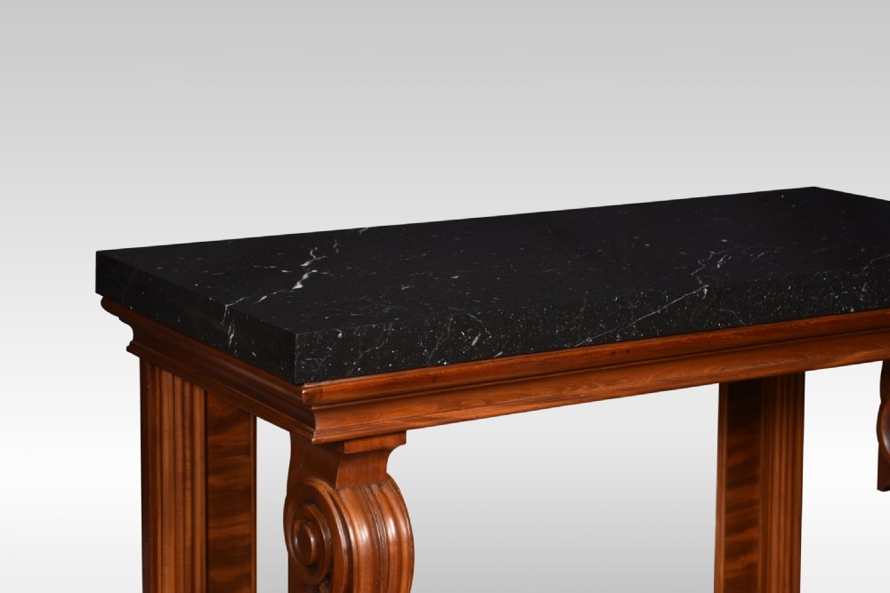 A Regency mahogany console table featuring a black marble top, scroll front legs with carved paw feet, a mirrored back plate, and a concave base. View V