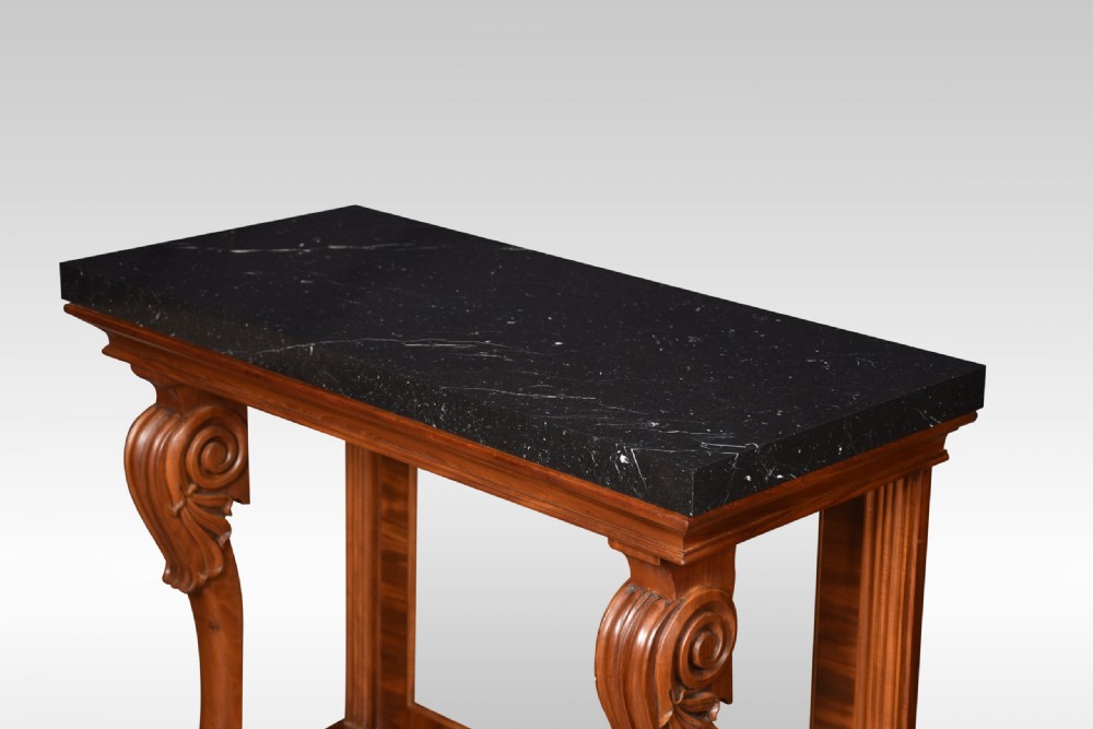 A Regency mahogany console table featuring a black marble top, scroll front legs with carved paw feet, a mirrored back plate, and a concave base. View VII
