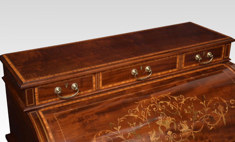 An antique mahogany cylinder desk featuring floral marquetry inlay, brass drop handles, square tapered legs, and an upper tier with drawers. View XI