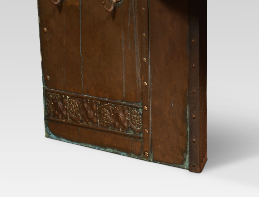 An Arts and Crafts period embossed copper fireplace insert featuring a central domed canopy, riveted construction, and foliage repousse panels. View III