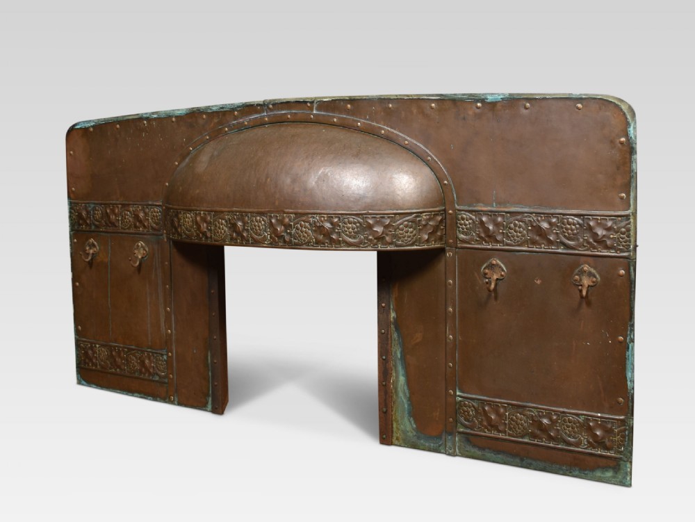 An Arts and Crafts period embossed copper fireplace insert featuring a central domed canopy, riveted construction, and foliage repousse panels. View IV