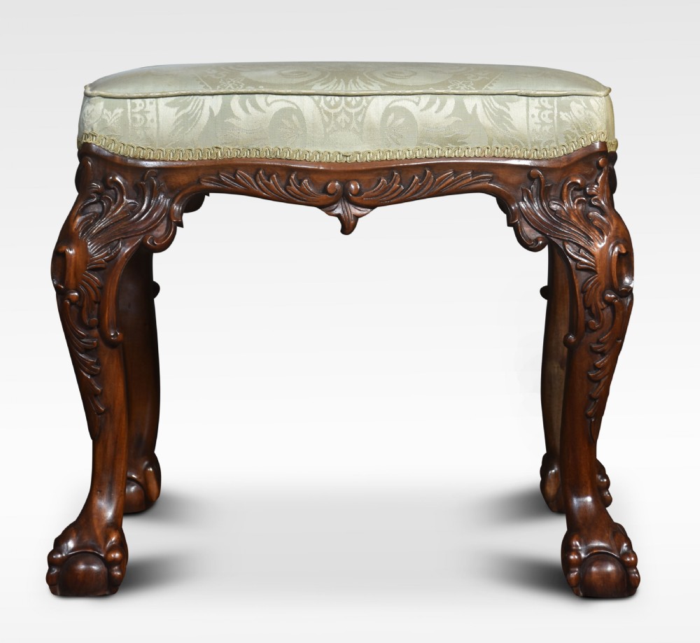 A mahogany Chippendale style stool with carved acanthus leaf cabriole legs, ball-and-claw feet, and a pale green damask upholstered top.