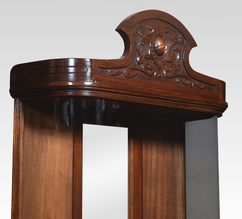 An antique mahogany bow-fronted display cabinet featuring curved glass sides, a mirrored back panel, and a carved cresting pediment at the top. View IV