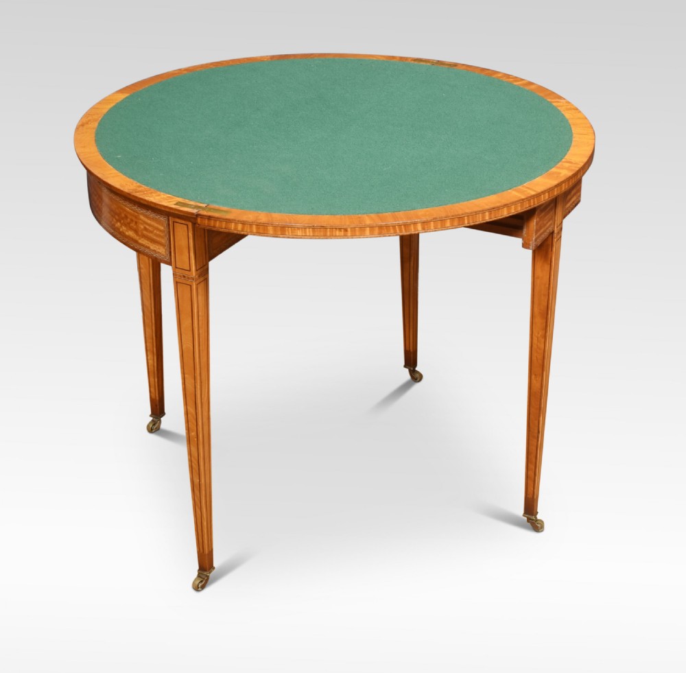 An antique semi-circular satinwood card table featuring inlaid crossbanding, tapered square legs, and small brass castors. View II