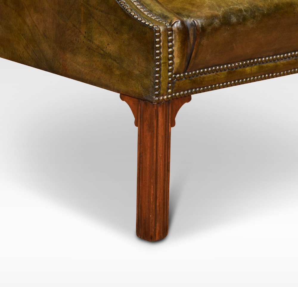 A classic high-backed armchair upholstered in aged brown leather with brass stud detailing and dark mahogany legs. View IV