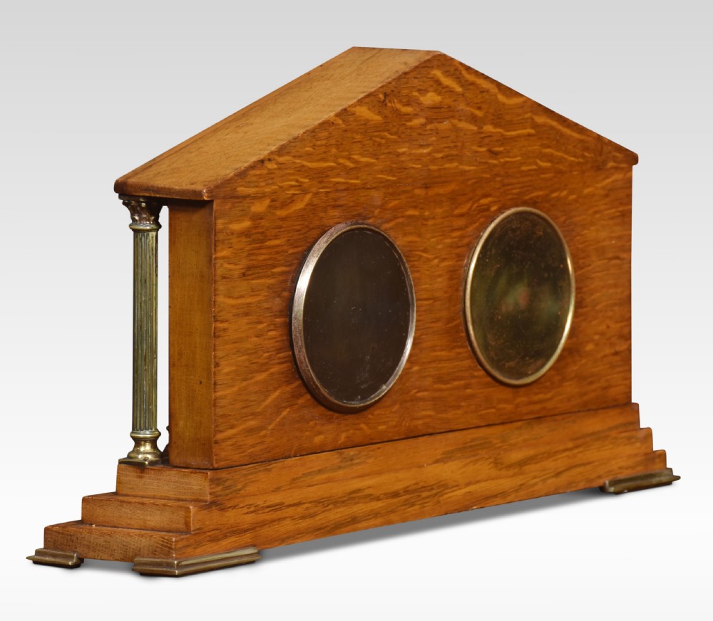 An architectural oak desk clock featuring a triangular pediment top, brass fluted columns, a central thermometer, and twin dials for a clock and barometer. View III
