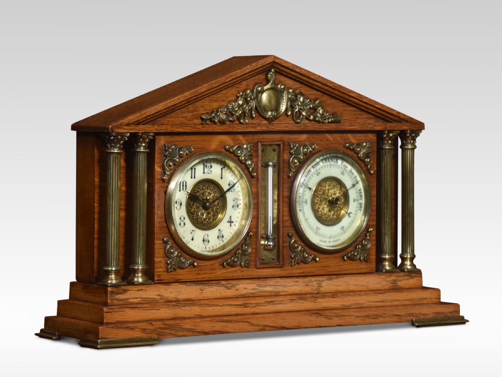 An architectural oak desk clock featuring a triangular pediment top, brass fluted columns, a central thermometer, and twin dials for a clock and barometer. View V