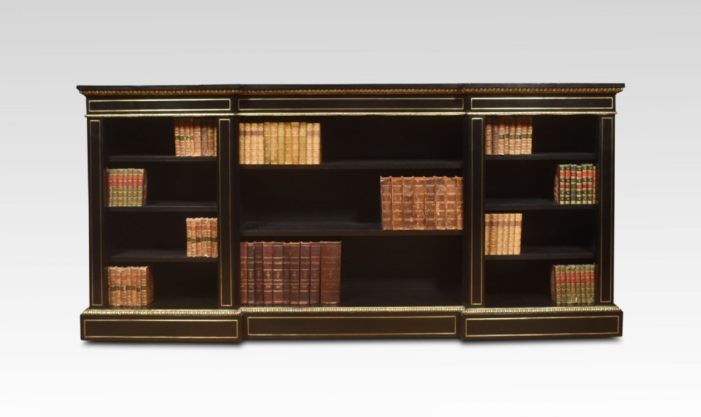 A large, low ebonised black wooden open bookcase featuring three sections outlined with decorative gilt brass mounts. View II