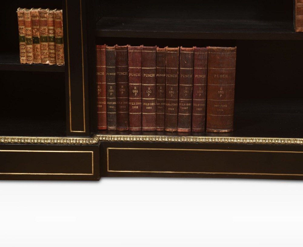 A large, low ebonised black wooden open bookcase featuring three sections outlined with decorative gilt brass mounts. View VIII